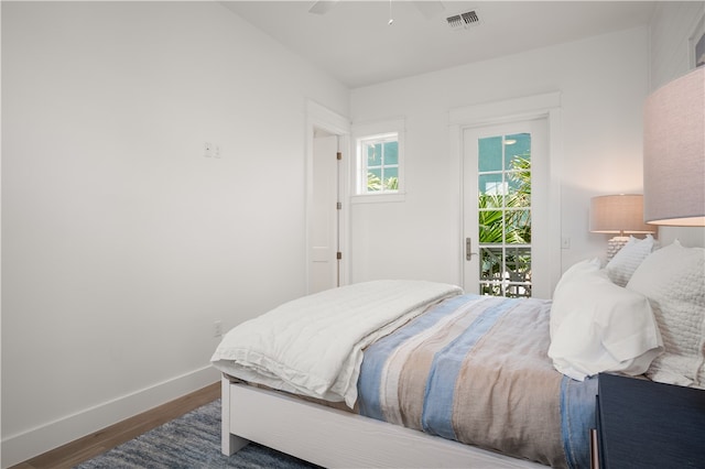 bedroom with wood finished floors, a ceiling fan, baseboards, visible vents, and access to exterior