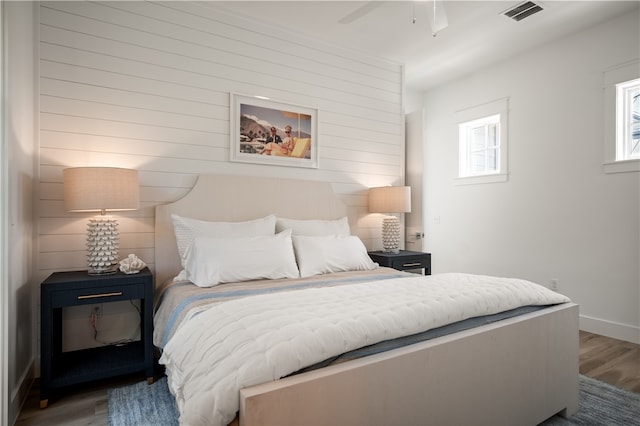 bedroom featuring a ceiling fan, baseboards, visible vents, and wood finished floors