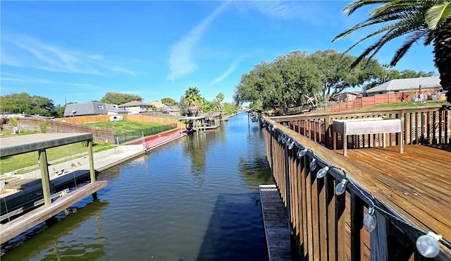 view of dock featuring a water view, boat lift, and fence