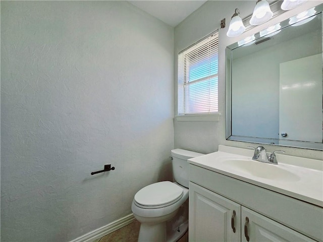 bathroom with baseboards, a textured wall, toilet, and vanity