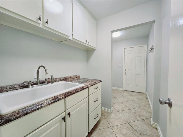 laundry room with baseboards, a sink, and light tile patterned floors