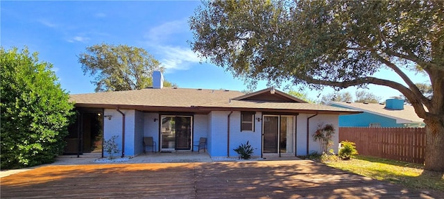 view of front of property with a shingled roof, a deck, fence, and brick siding