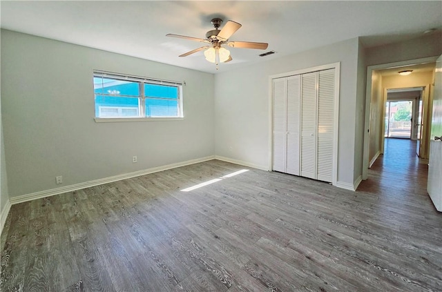 unfurnished bedroom featuring baseboards, ceiling fan, wood finished floors, and a closet