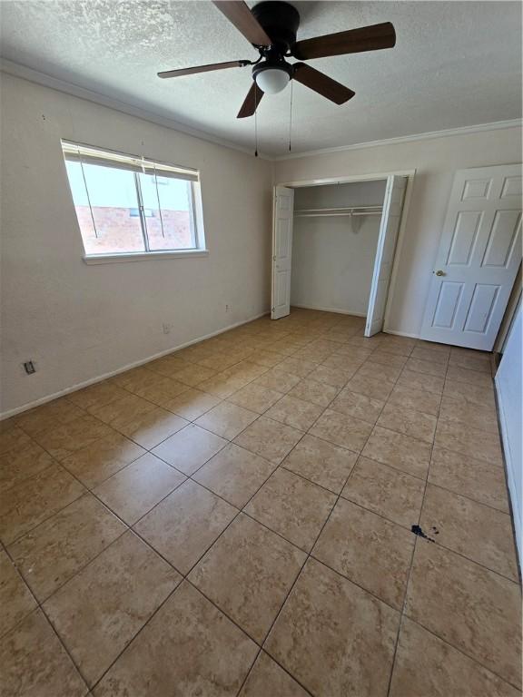 4109 Eagle Dr, Corpus Christi, TX 78413 - unfurnished bedroom with crown molding, a textured ceiling, a closet, light tile patterned floors, and a ceiling fan