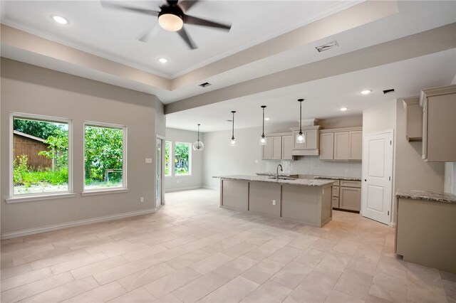 kitchen featuring a center island with sink, sink, ceiling fan, light stone countertops, and pendant lighting