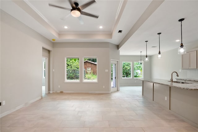 unfurnished living room with ornamental molding, light tile patterned floors, a raised ceiling, sink, and ceiling fan