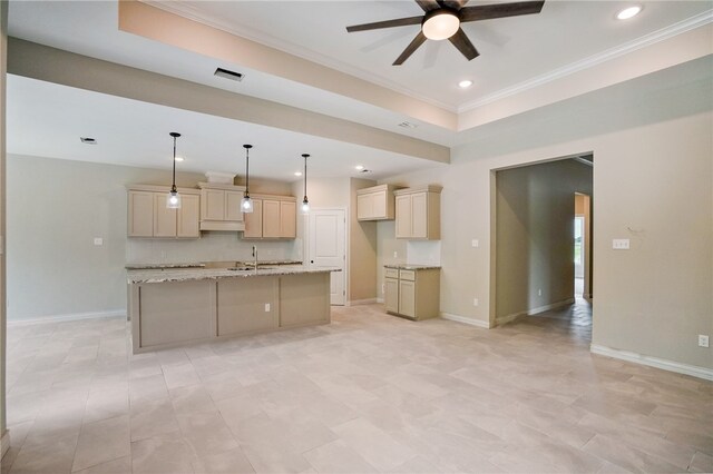 kitchen with light stone countertops, sink, an island with sink, and crown molding