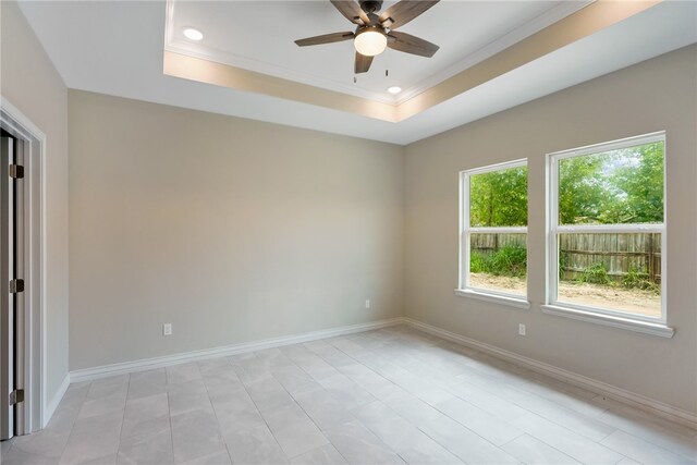 empty room with a tray ceiling, ceiling fan, and crown molding