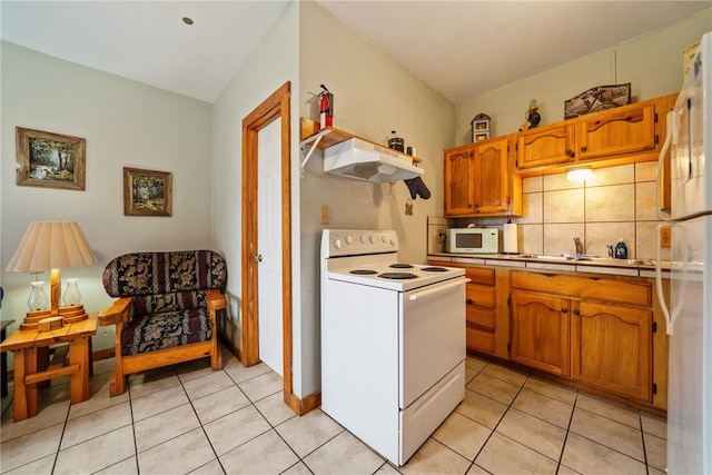 kitchen with light tile patterned floors, backsplash, white appliances, range hood, and lofted ceiling