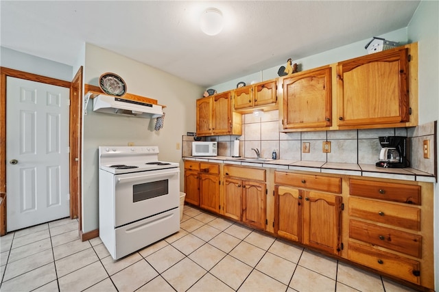 kitchen with tile countertops, decorative backsplash, light tile patterned floors, sink, and white appliances