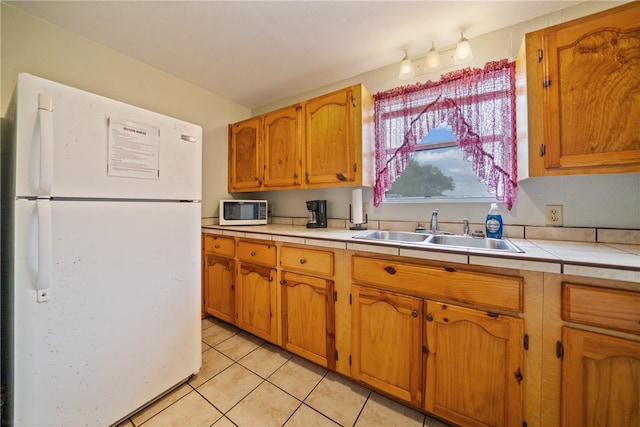 kitchen featuring tile countertops, white appliances, sink, and light tile patterned floors