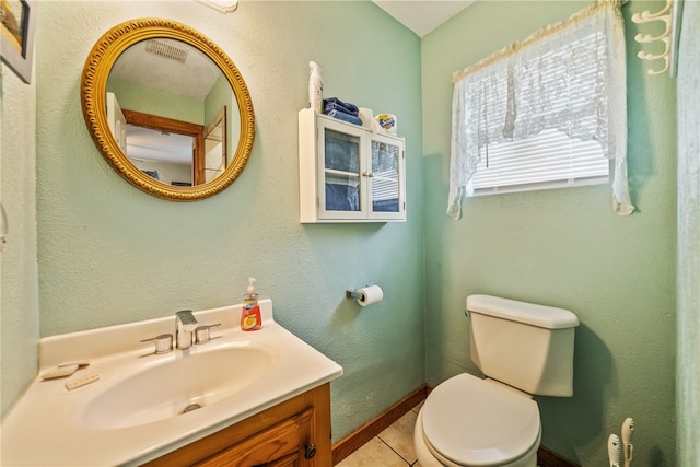 bathroom with toilet, vanity, and tile patterned floors