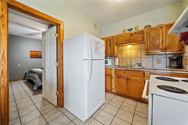 kitchen featuring light tile patterned floors, sink, backsplash, extractor fan, and white appliances