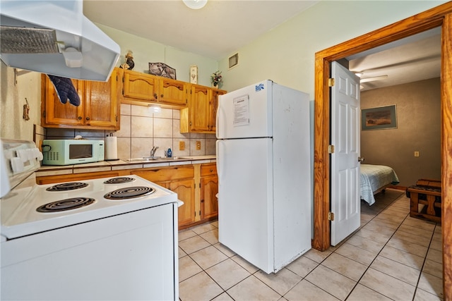 kitchen with decorative backsplash, sink, light tile patterned flooring, extractor fan, and white appliances