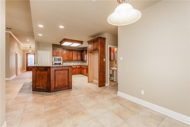 7510 Beau Terre, Corpus Christi, TX 78414 - kitchen featuring stainless steel microwave, brown cabinetry, baseboards, decorative backsplash, and light tile patterned flooring