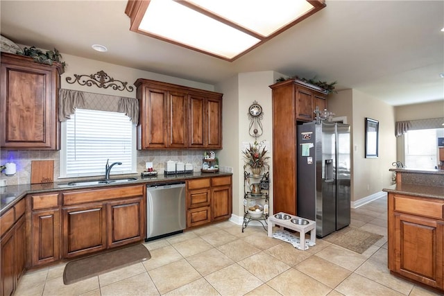 kitchen with backsplash, sink, light tile patterned floors, and stainless steel appliances