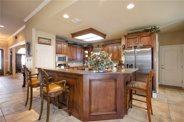 kitchen featuring a breakfast bar, decorative backsplash, a center island, and stainless steel appliances