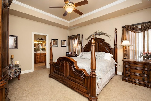 carpeted bedroom with a raised ceiling, connected bathroom, ceiling fan, and ornamental molding