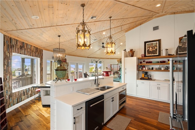 kitchen with a center island with sink, white cabinets, vaulted ceiling, appliances with stainless steel finishes, and decorative light fixtures