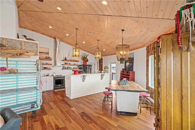 kitchen featuring a kitchen breakfast bar, pendant lighting, a center island with sink, hardwood / wood-style floors, and white cabinetry