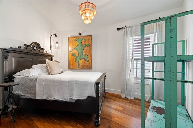 bedroom with hardwood / wood-style flooring and an inviting chandelier