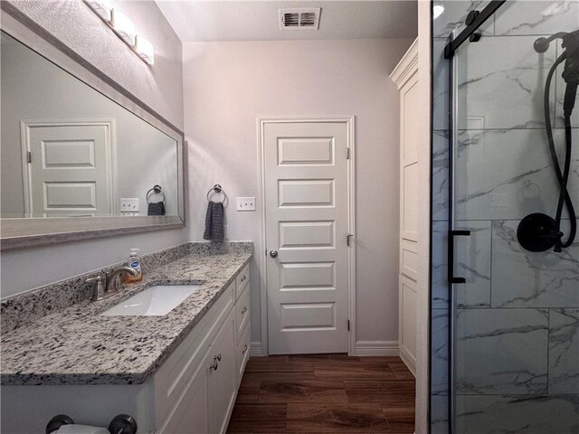 2521 Handlin Dr, Corpus Christi, TX 78418 - bathroom featuring baseboards, visible vents, vanity, wood finished floors, and a marble finish shower