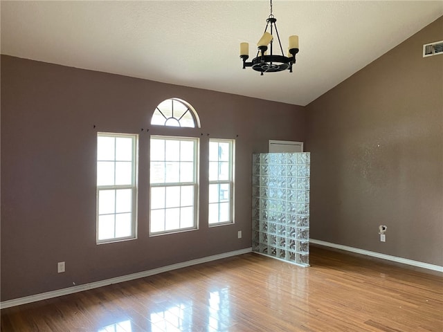 unfurnished room with light wood-type flooring, lofted ceiling, a textured ceiling, and a notable chandelier