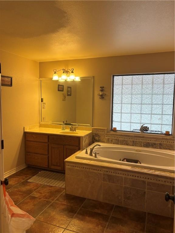 bathroom featuring vanity, a relaxing tiled tub, and tile patterned floors