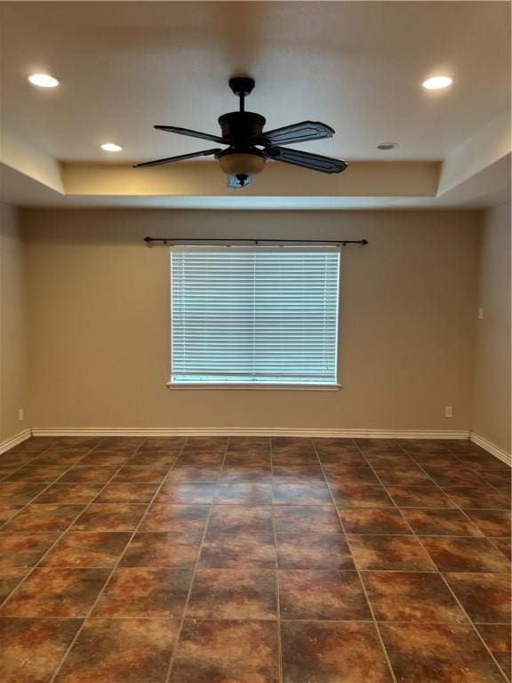 spare room featuring a raised ceiling and ceiling fan