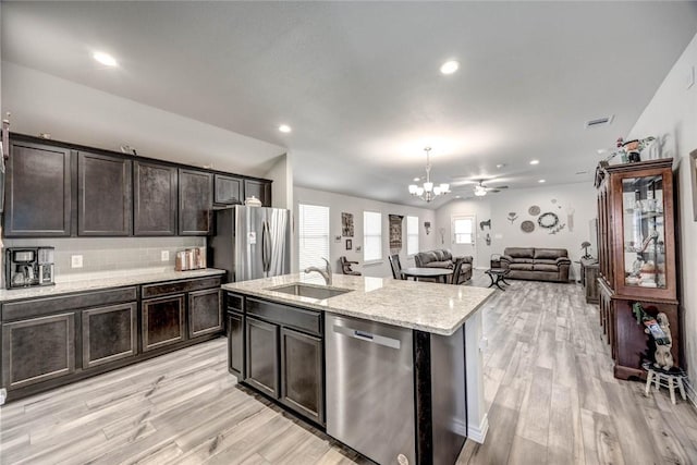 kitchen featuring appliances with stainless steel finishes, an island with sink, sink, lofted ceiling, and ceiling fan with notable chandelier