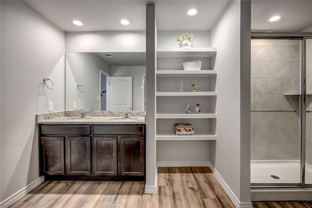 bathroom with a shower with door, vanity, hardwood / wood-style floors, and built in features