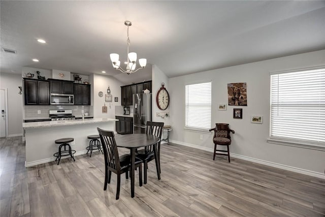 dining space with an inviting chandelier and light hardwood / wood-style flooring