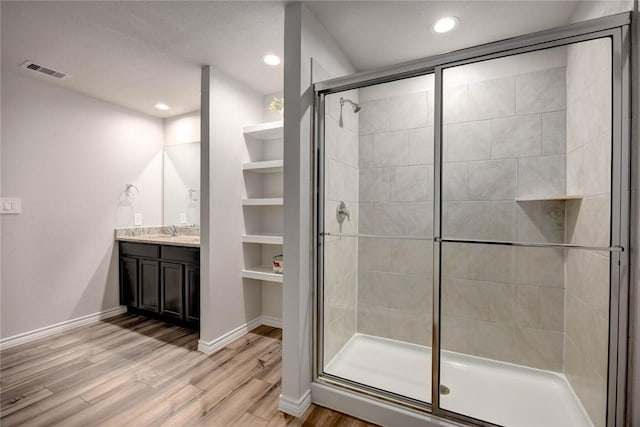 bathroom featuring an enclosed shower, built in features, wood-type flooring, and vanity