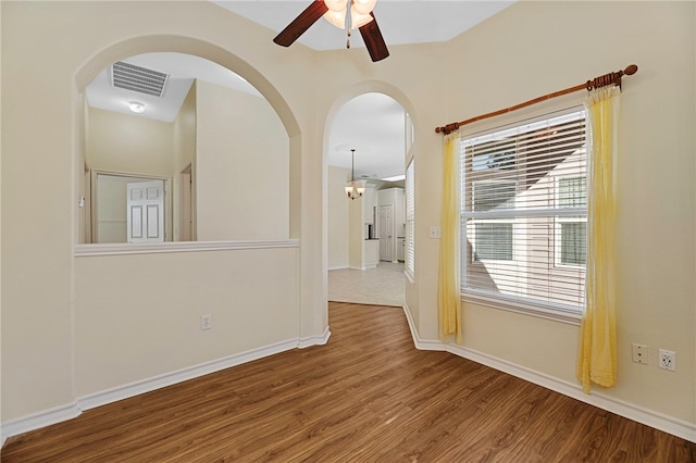 empty room with hardwood / wood-style floors and ceiling fan with notable chandelier