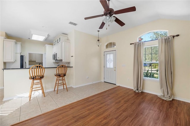 126 Whistlers Cove Rd, Rockport, TX 78382 - kitchen with dark countertops, vaulted ceiling, light wood-style flooring, a breakfast bar area, and a peninsula