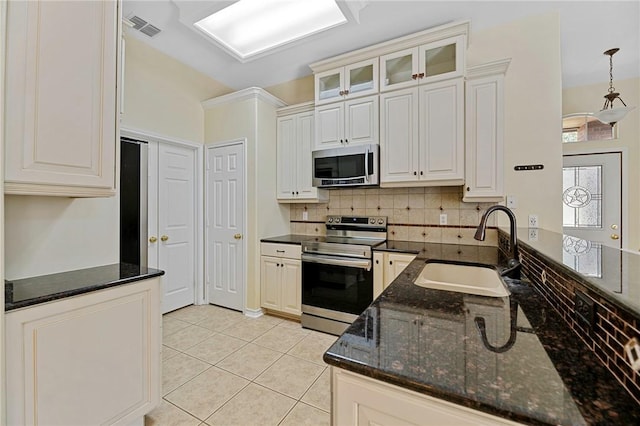 126 Whistlers Cove Rd, Rockport, TX 78382 - kitchen featuring appliances with stainless steel finishes, a sink, dark stone countertops, glass insert cabinets, and tasteful backsplash