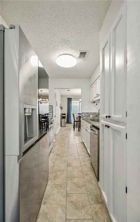 2722 Camargo Dr, Corpus Christi, TX 78415 - kitchen with appliances with stainless steel finishes, white cabinetry, a textured ceiling, and light tile patterned flooring