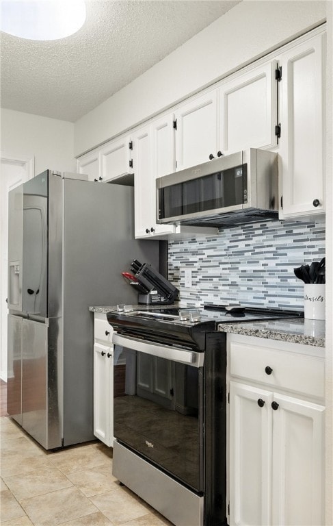 2722 Camargo Dr, Corpus Christi, TX 78415 - kitchen with appliances with stainless steel finishes, white cabinets, a textured ceiling, tasteful backsplash, and light tile patterned floors
