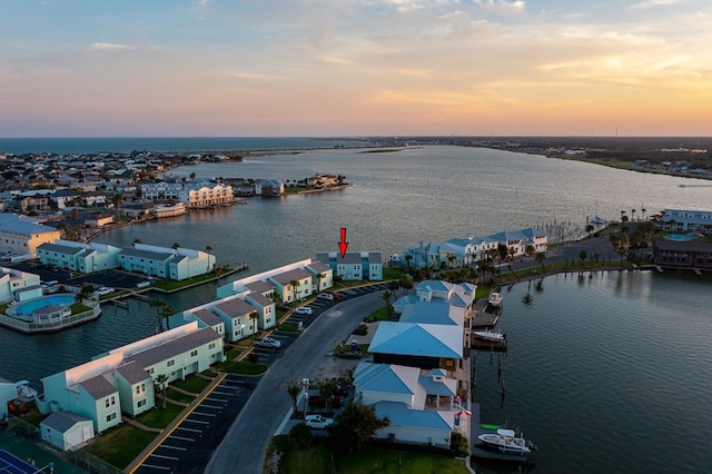 aerial view at dusk featuring a water view