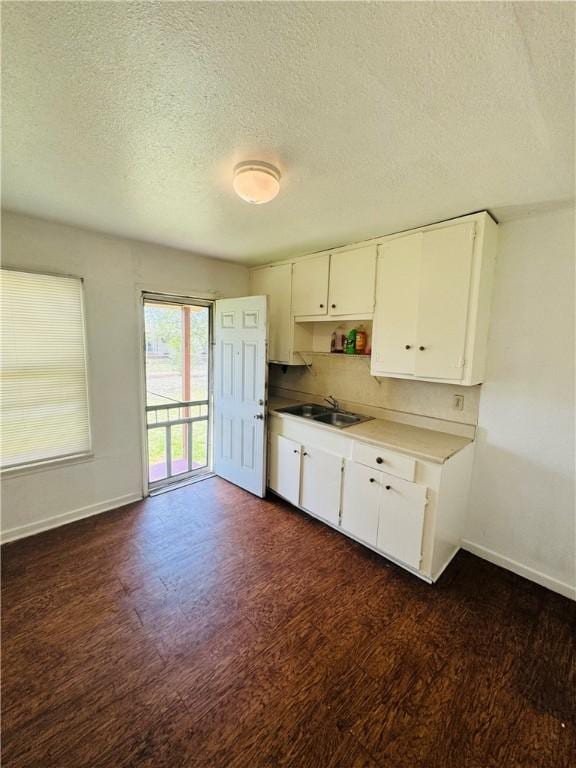 1725 Sycamore Pl, Corpus Christi, TX 78416 - kitchen featuring a sink, a textured ceiling, dark wood finished floors, baseboards, and white cabinets