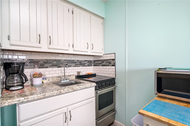 kitchen featuring white cabinetry, stainless steel electric range oven, tasteful backsplash, and sink