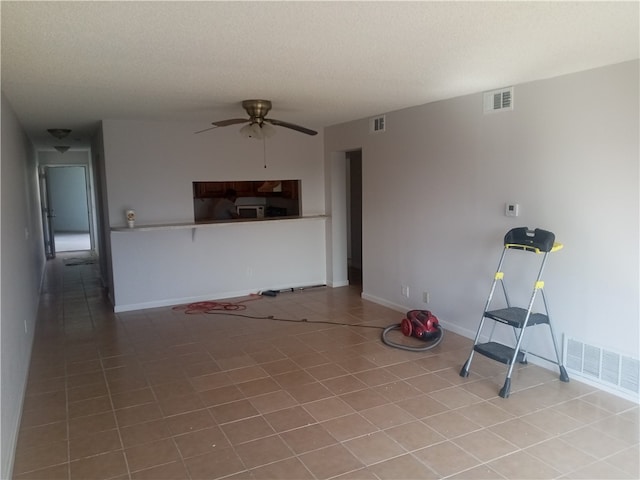 unfurnished living room featuring a textured ceiling, light tile patterned floors, and ceiling fan