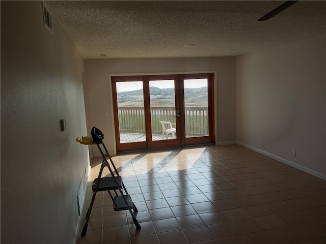 spare room featuring a water view, a textured ceiling, and tile patterned floors