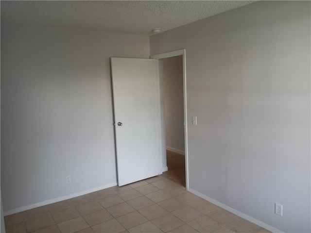 spare room with a textured ceiling and light tile patterned floors