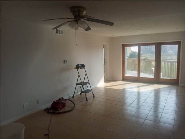 tiled empty room with ceiling fan and a textured ceiling