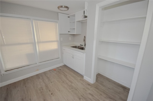 kitchen with sink, white cabinets, and light hardwood / wood-style flooring