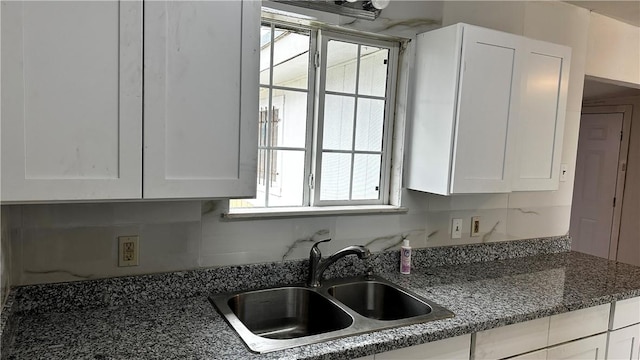 kitchen featuring dark countertops, a sink, and white cabinetry