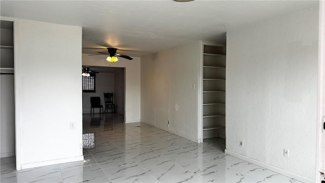 spare room featuring marble finish floor, a ceiling fan, and baseboards