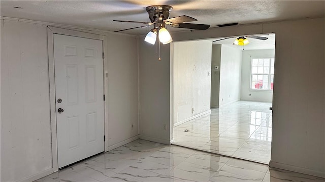 spare room with visible vents, baseboards, ceiling fan, marble finish floor, and a textured ceiling