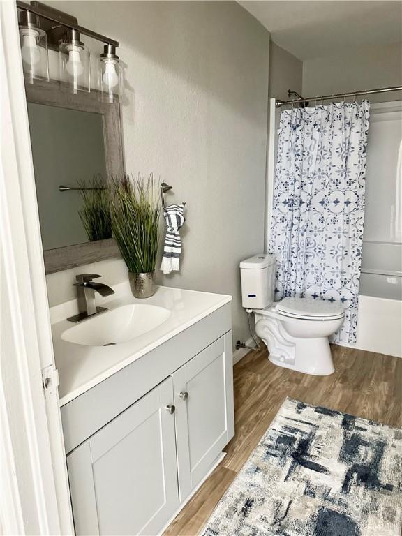 full bathroom with shower / bath combo with shower curtain, vanity, wood-type flooring, and toilet